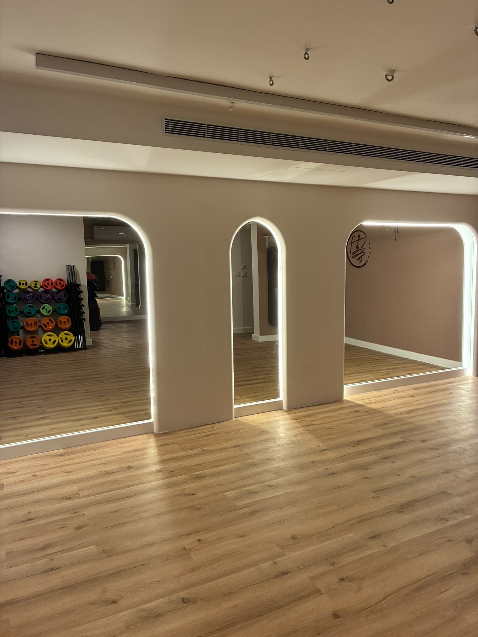 The studio, with arched lit mirrors and a wooden floor